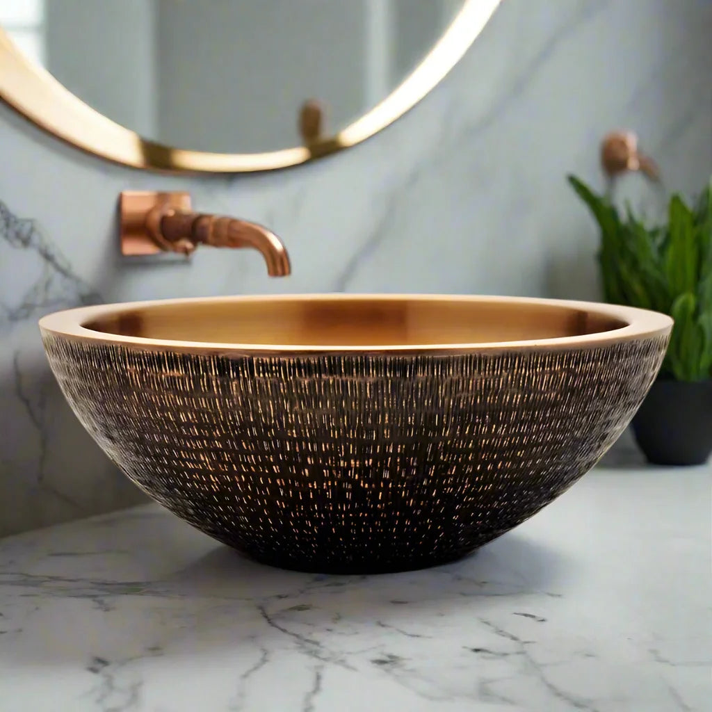 Copper basin with copper spout in luxurious bathroom with marble wall and vanity top next to a mirror