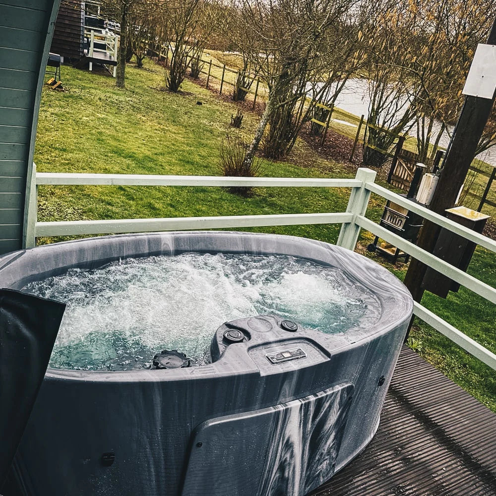 Just for two hot tub on a outdoor patio next to green field