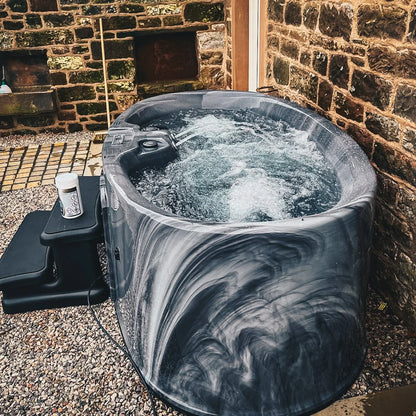 Just for two hot tub in outdoor setting with steps next to it.